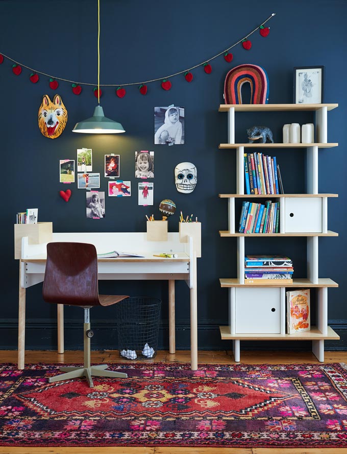 A navy blue bedroom with a kids desk and a bookcase next to it. Image: Cuckooland.