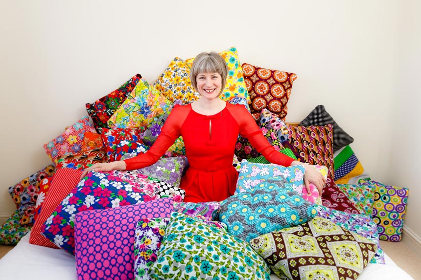 Fritha Mason, the founder of Secret Projects, sitting and surrounded by a pile of Secret Pillows. Image: Secret Projects copyright Julia Neal.