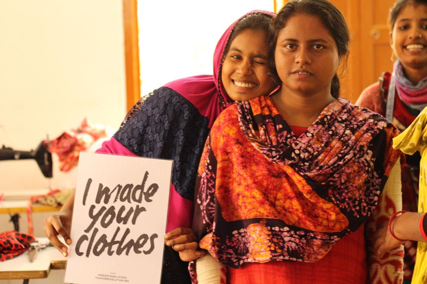 Two young women from India holding up a sign that reads 'I made your clothes.' Image: Secret Projects.