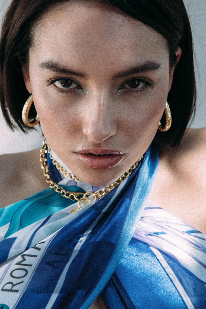 A woman with a bob hairstyle, wearing the Kitty hoop earrings and a layered chain necklace. Photo credit: MOUNTAIN & MOON. Photographer: Tijana Lilic.