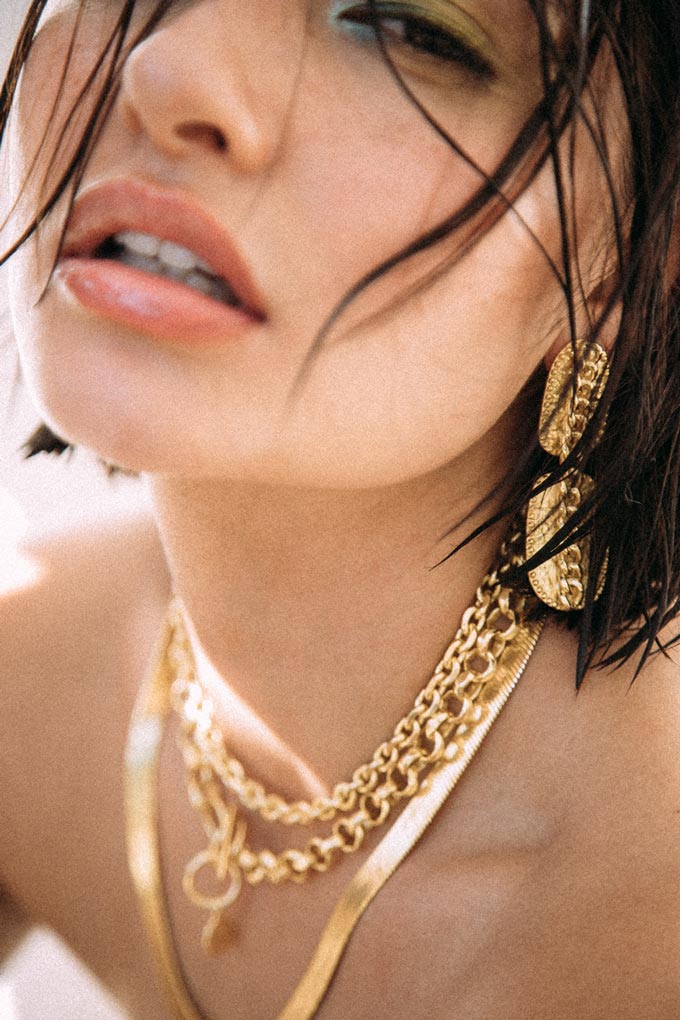 Sexy close up of woman wearing pendant golden earrings and chain necklaces. Photo credit: MOUNTAIN & MOON. Photographer: Tijana Lilic.
