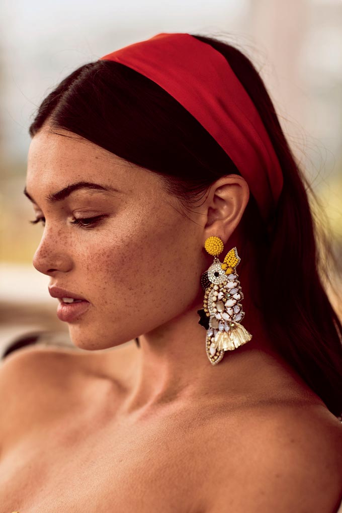 Woman with a red head band and a statement earring. Image by Accessorize.
