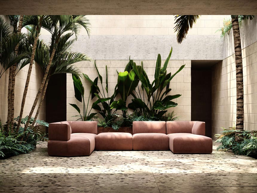 A modular contemporary sofa in a blushed pink velvet fabric resting on terrazzo tiles with lots of big green plants on the side and at the background. Image: Domkapa.