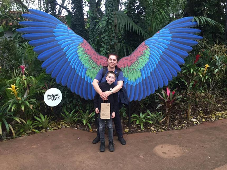 Eva and son Michael standing in front of a set of blue wings for a snapshot while in a National Park during their trip in Argentina.