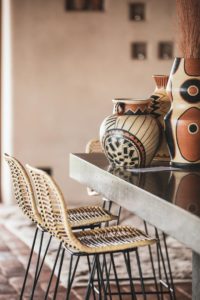 Ceramics with patterns in earth tones is another brilliant way to decorate. A summery setup with rattan dining chairs and ceramic vases on a grey dining table. Image: OZ Design Furniture.