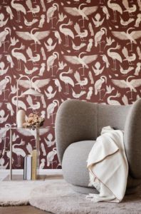 A fab looking light grey armchair in front of a pattern brown wallpapered wall. Image: Nest.co.uk.