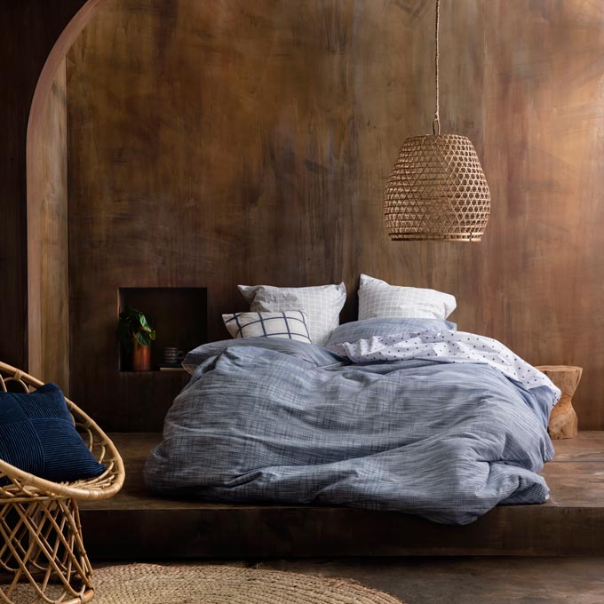 A stunning bedroom with brown walls and a bed with blue linens. A fantastic combo. Image: KAS Australia.