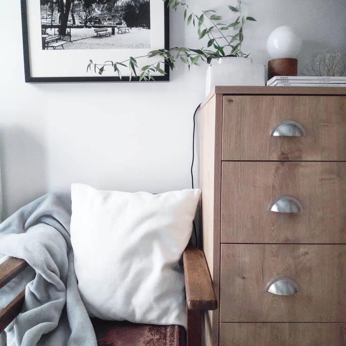 A partial view of a dresser with a director's chair that looks comfy thanks to a pillow and a soft n fluffy throw.