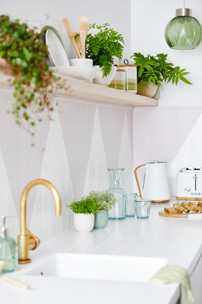 Partial view of a white kitchen with a brass faucet and open kitchen shelving. Image: Dunelm.