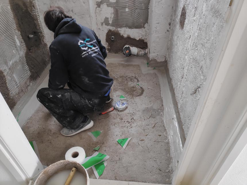 Top Design Crimes. Here: A workman applying a much required waterproofing layer in a bathroom under renovation between and wall and floor in one of my client projects.