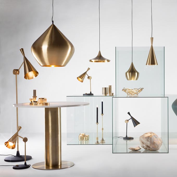 Various types of brassy lighting fixtures and Tom Dixon's round table with a tube like brassy stand. Image: Amara.