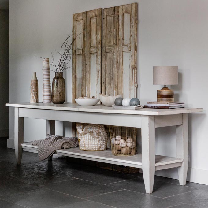A vignette sporting a reclaimed wooden door behind a large console table. Image: Amara.