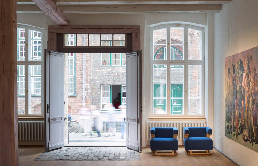 A large space with a very high ceiling and tall windows featuring two blue Gropius F51 Sessel Bauhaus Tecta chairs via einrichten-design.de.