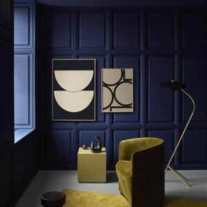 An all navy blue room featuring on olive khaki velvet armchair, an area rug and two Bauhaus inspired art prints on the wall. Via Nest.co.uk.