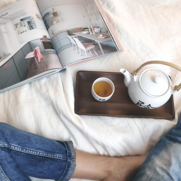 Flatlay image of Velvet drinking tea and reading an interiors magazine.