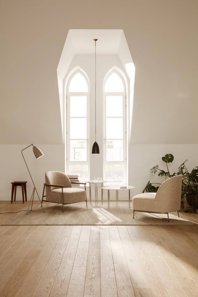 A warm minimal setting by a large window featuring two Mid-Century inspired chairs. Via Chaplins.