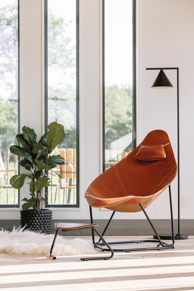 The Abrazo leather armchair and its stool featured in a well lit interior. Via Nest.co.uk.