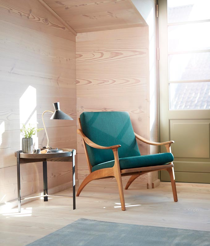 A warm Nordic vignette by a large window door, featuring a Mid-Century armchair. Via Nest.co.uk.