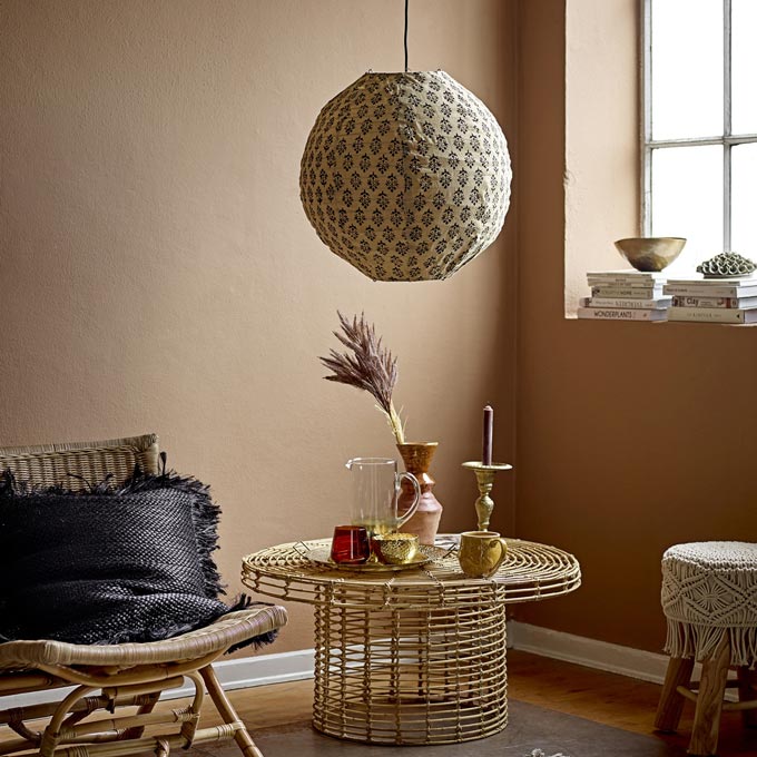 A rattan-wicker styled vignette featuring an armchair, a stool and a round coffee table. Via Amara.
