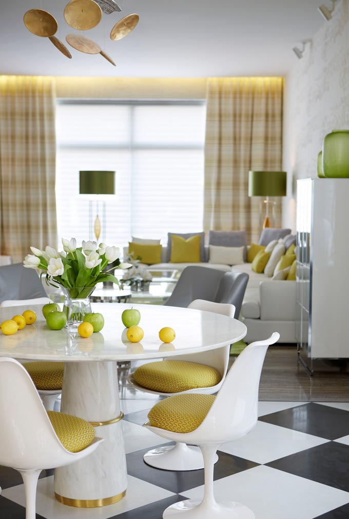 A bright dining space in the foreground and a sitting room in the background featuring yellow and gray color accents. Via Brabbu Design Forces.