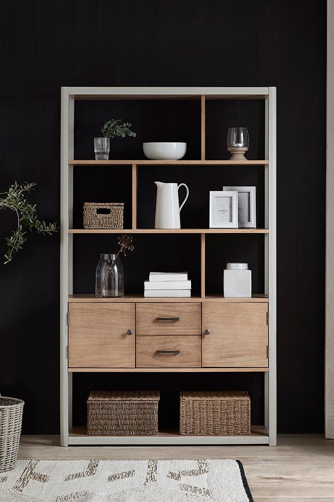 A stylish bookcase styled with neutral toned decor against a black wall. Image via Next.