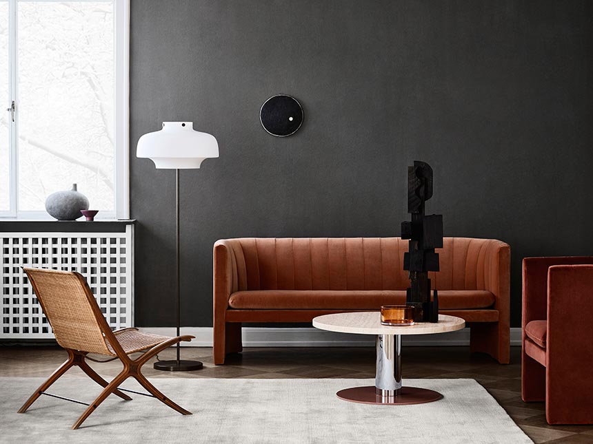 A contemporary moody interior with an airy rusty hue velvet sofa and armchair and a round coffee table. Image via Nest.