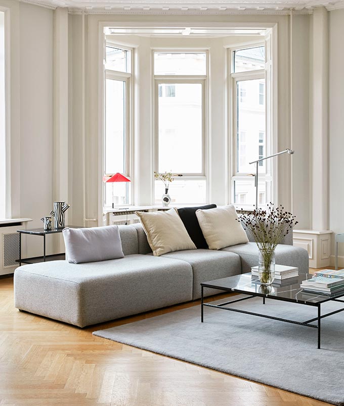 A bright contemporary living room with a modular light grey sofa and a black marble top coffee table. Image via Nest.co.uk.