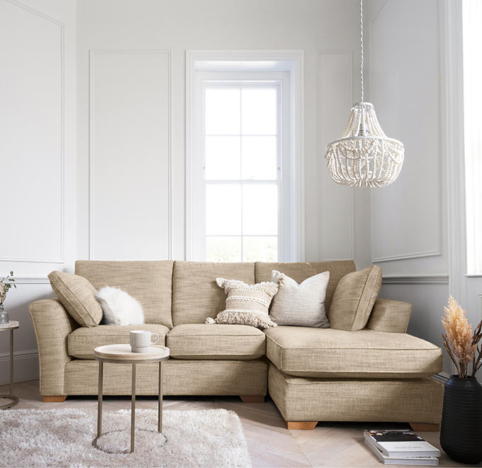A beige sectional in a small off white room looking stylish despite its bulkiness. Image via Next.