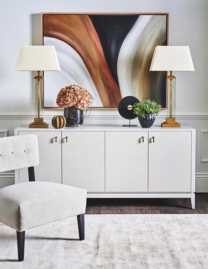 A luxurious looking off white vignette with a sideboard and a large artwork over it. Image via Luxdeco.