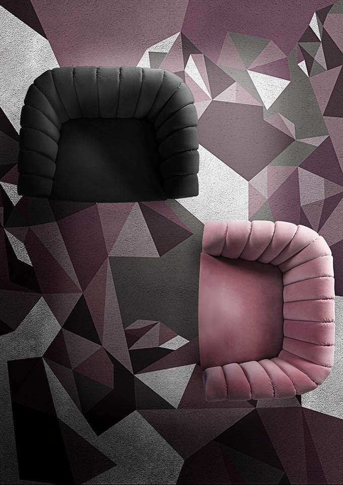 An eye bird view of two velvet armchairs (one in charcoal gray the other in pink) atop a geometric pattern rug with moody pinks and grays. Via Brabbu Design Forces.