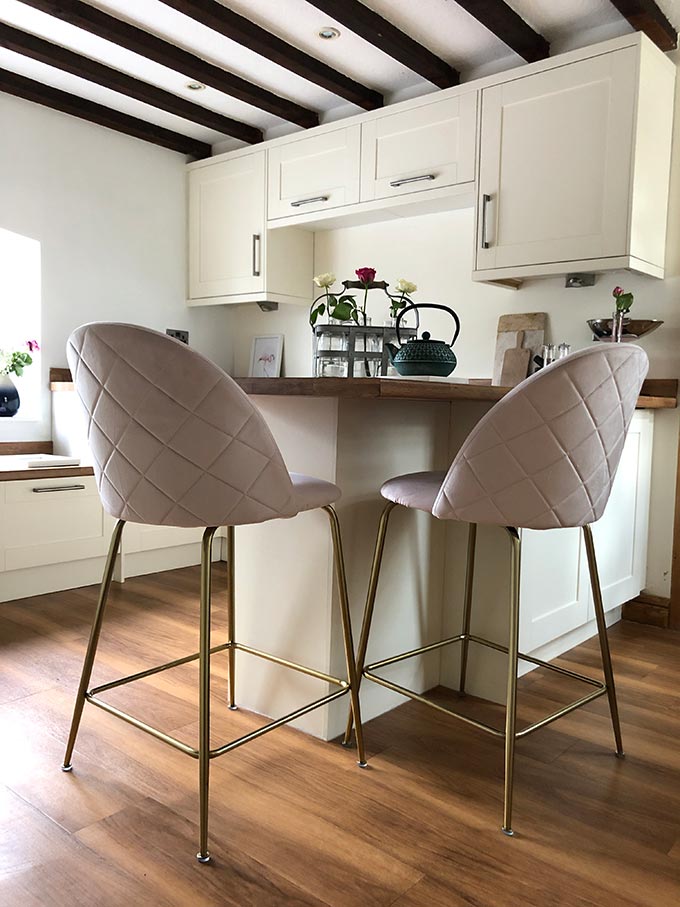 A contemporary off white kitchen with a twist: two dusty pink bar stools upholstered in velvet. Via Cult Furniture.