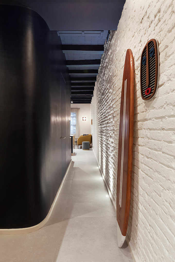 View of a bold corridor of a small apartment in Barcelona, with a navy blue ceiling and wall. Image: Elton Rocha for Culto.