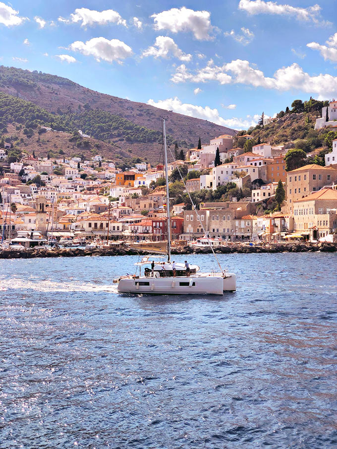 View of Hydra in the background and a sailing boat in foreground. Image: Despina Galani on Unsplash.