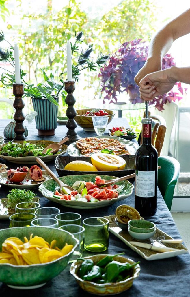 View of a large dining table filled with beautiful food platters and dished. Via STHAL.