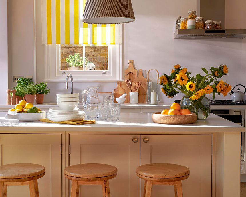 A joyful vibrant kitchen with yellow pops of color and a vase with sunflowers on the kitchen island. Spring home styling at its finest. Image: Homesense.