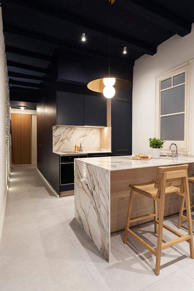 View of a contemporary navy blue kitchen with a marble counter and backsplash. Image: Elton Rocha for Culto.