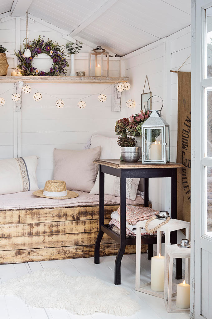 A white room with a spring styling rustic aesthetic, lanterns and a string of lights hanging over a DIY looking sofa. Image: Lights4fun.