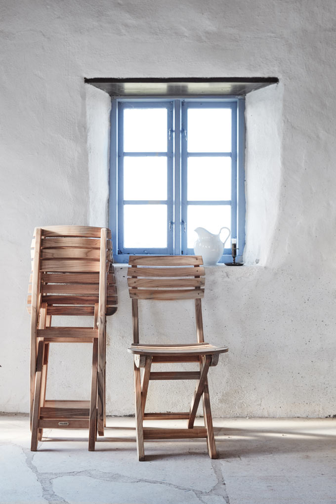 The Vendia chairs by Skagerak in front of a white washed wall and a blue window. Image: Skagerak.