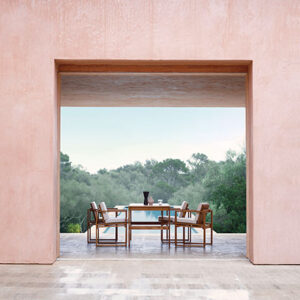 The Carl Hansen BK10 outdoor dining setup in the foreground and a pool in the background. Image: Nest.co.uk.