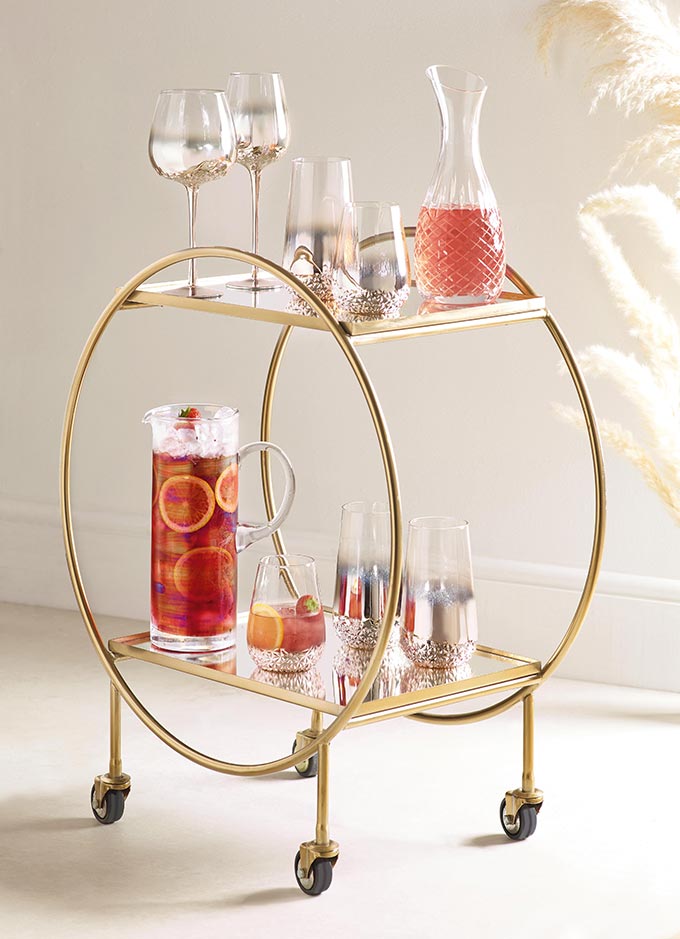 A bar cart trolley with fruit punch decanters, glasses and all. Via Next.