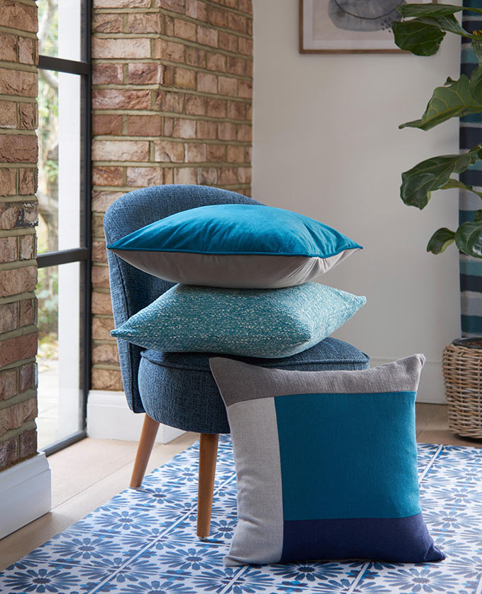 A blue chair with three different blue pillows on it. Image: Next.
