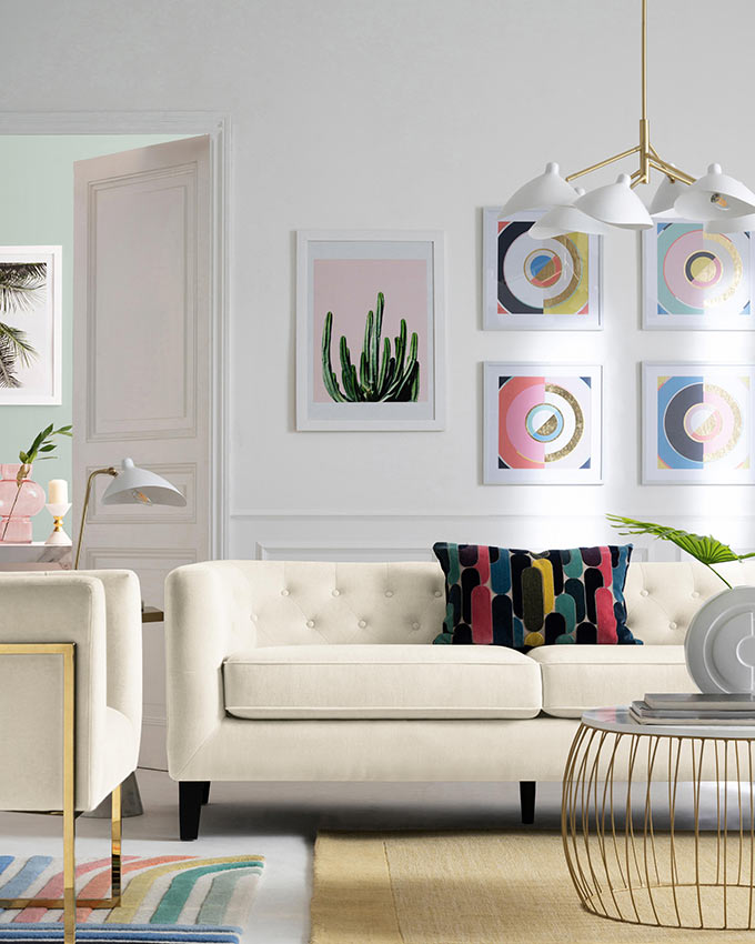 A stylish white living room with a pop vibe to it and a gallery art wall behind the off-white sofa. Image: Next.