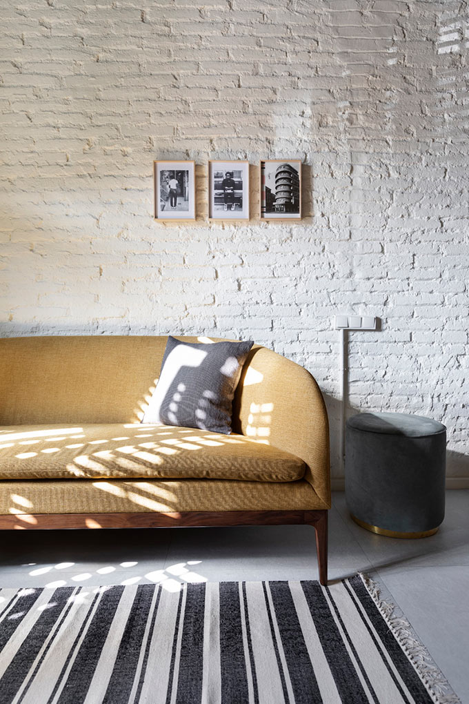 A curvy mustard sofa against that white washed exposed brick wall in perfect harmony. Image: Elton Rocha for CULTO.