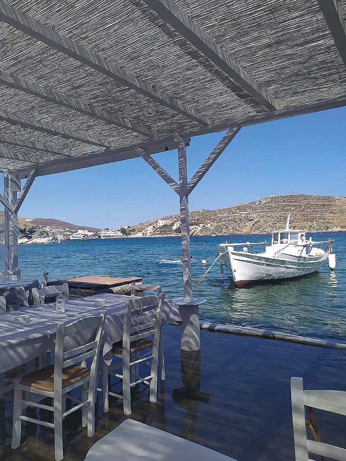 A shaded dining setup by the seashore at Axladi, Syros.