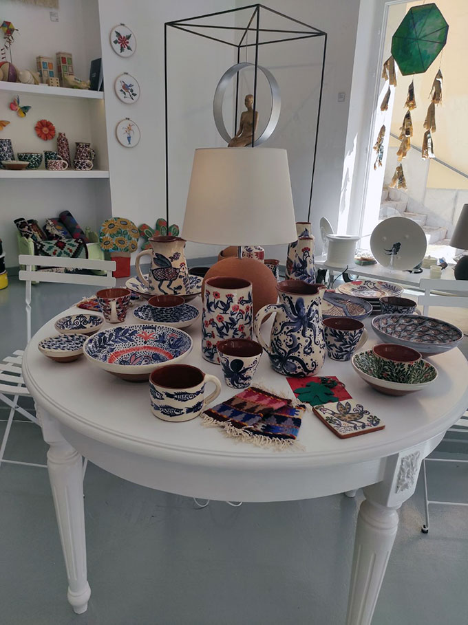 Handmade pottery artifacts on display on a table and shelves on the wall from Chimaira an Arts and Crafts shop in Syros.