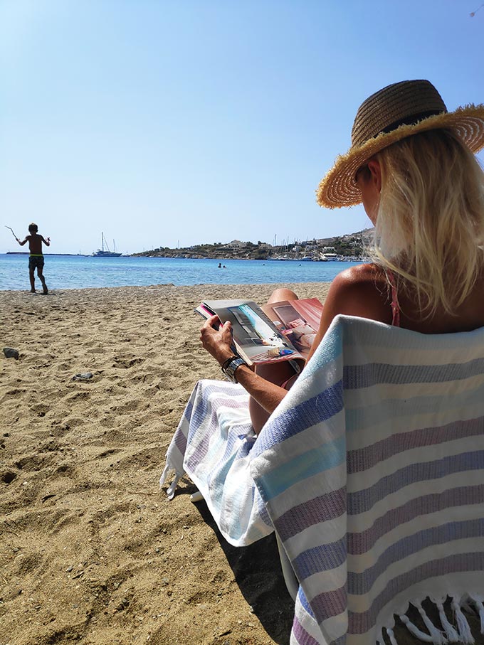 Elisabeth reading a mag while seating at the beach of Finikas.