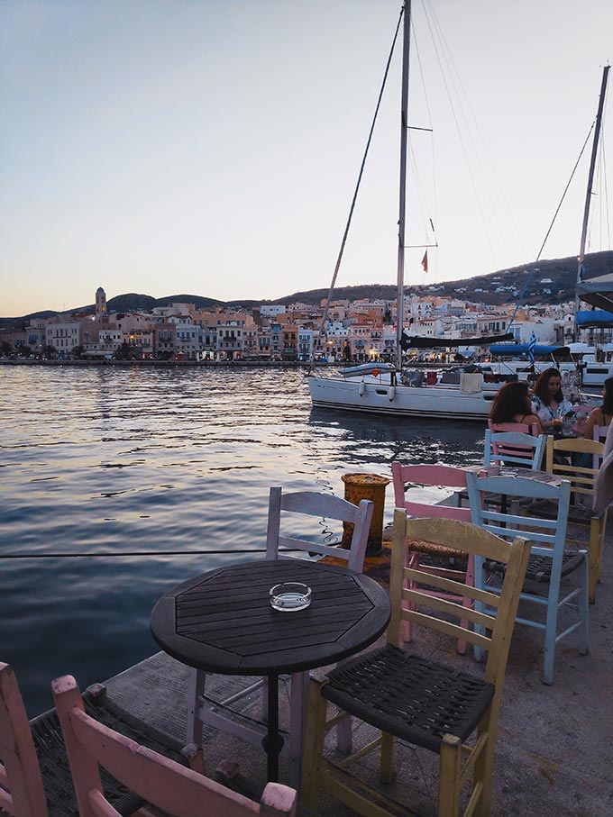 Sea view with sailing boats in the background from a coffee houses outdoor setup overlooking the port of Hermoupolis.