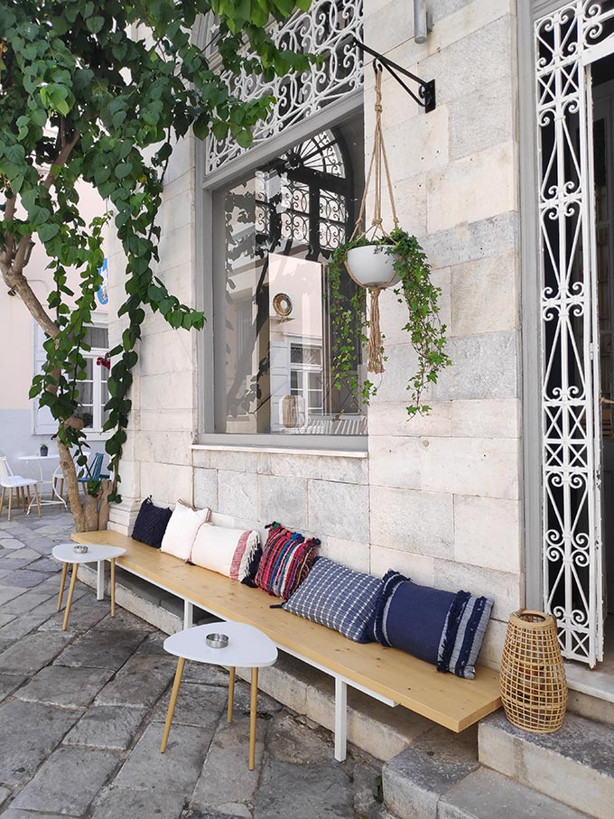 An outdoor seat bench in front of a masonry facade of an old building in Hermoupolis.