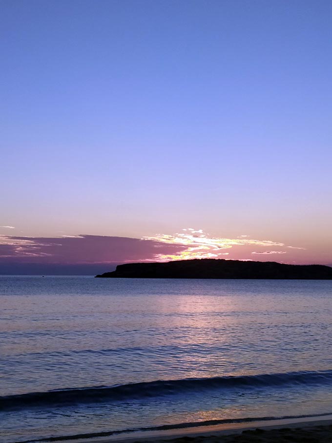 The beach of Delfini in Syros at sunset.