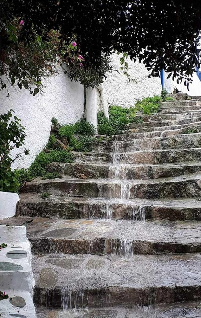 Stone paved stairs with water running down them.